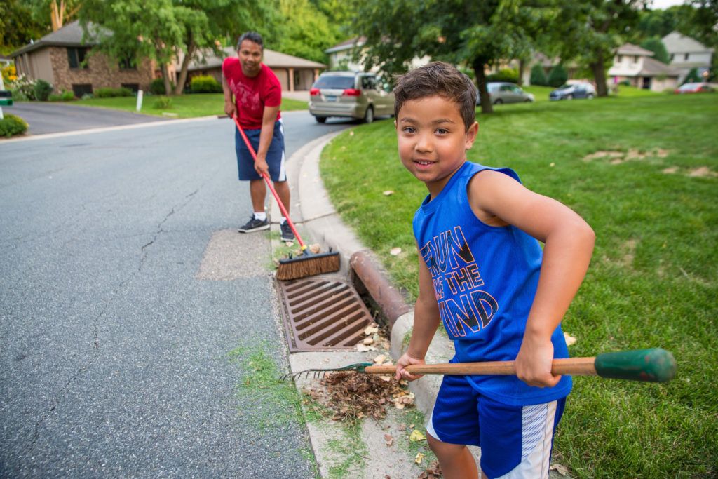 Two kids removing debris from a stormdrain.