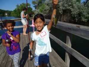 Girl holds up a fish on a line