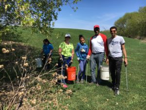 Image of 5 people standing in a grassy area with buckets and trash grabbers.