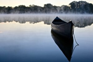A canoe in water, with fog in the background.