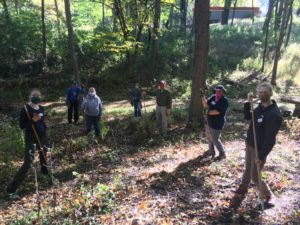 A group of people with rakes stand in a forest