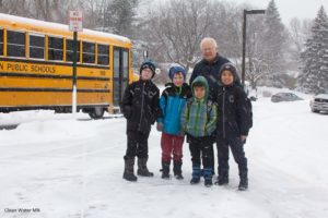 students pose by a bus on a snowy sidewalk