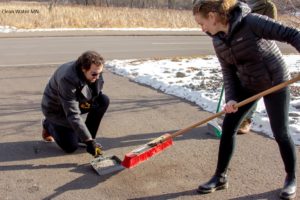 Two people sweep up extra salt