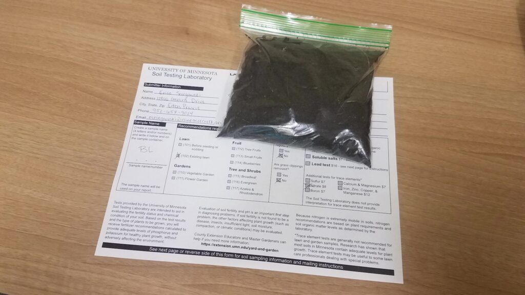 A baggie of soil on a table with a testing sheet underneath.