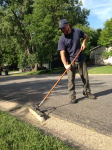 image of man sweeping grass clippings into yard