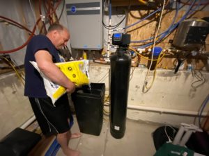 Man pouring salt into a residential water softener